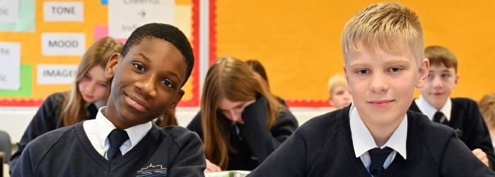 Two students sat at their desk looking at the camera